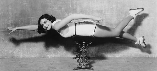 Dry Swim. circa 1930: A model lies across a stool to demonstrate a swimming stroke