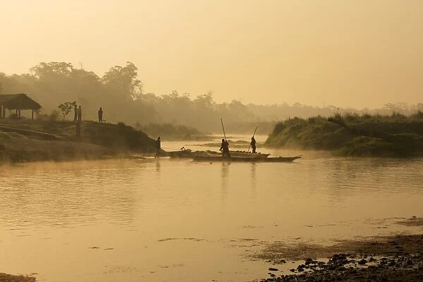Dugout canoe with punting ferryman crossing a small river early in the morning, rising sun and fog, Chitwan National Park, Nepal, Asia