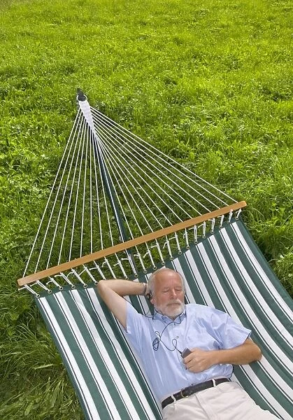Elderly gentleman lying in a hammock and listening to music