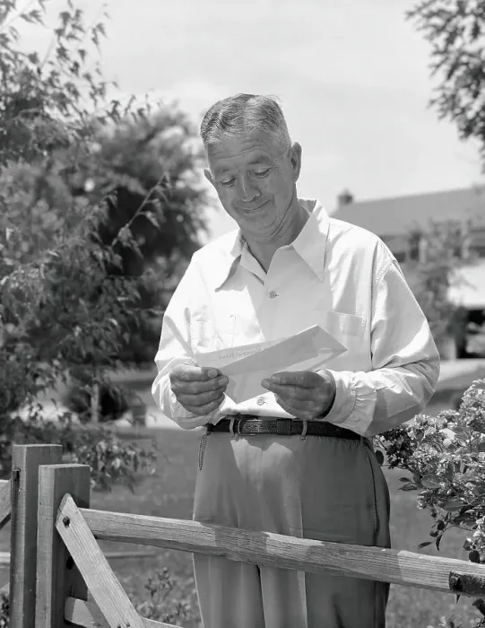 Framed Print : Elderly man standing by fence in yard, opening envelope and taking out cheque Framed Print : Elderly man standing by fence in yard, opening envelope and taking out cheque