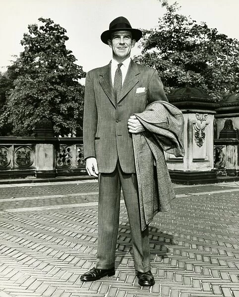 Elegant man carrying overcoat courtyard, (B&W)