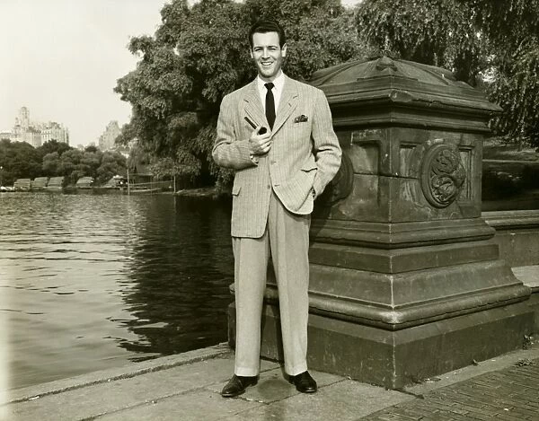 Elegant man with pipe by park lake, (B&W), portrait