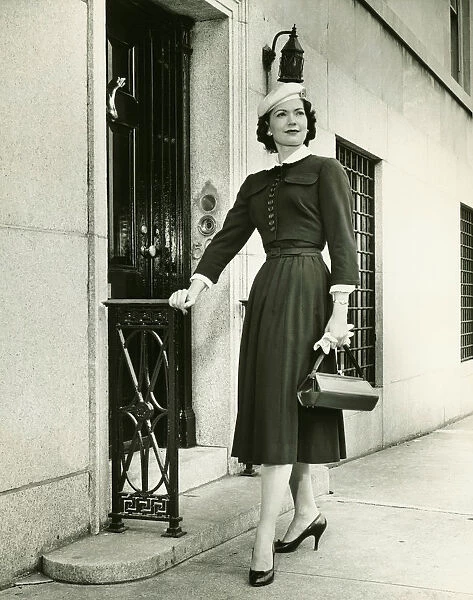 Elegant woman posing at building entrance, (B&W), portrait