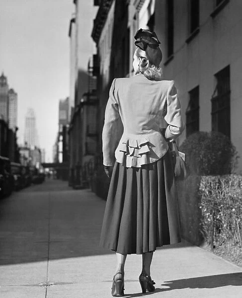 Elegant woman standing alone on sidewalk, Rear view, (B&W)