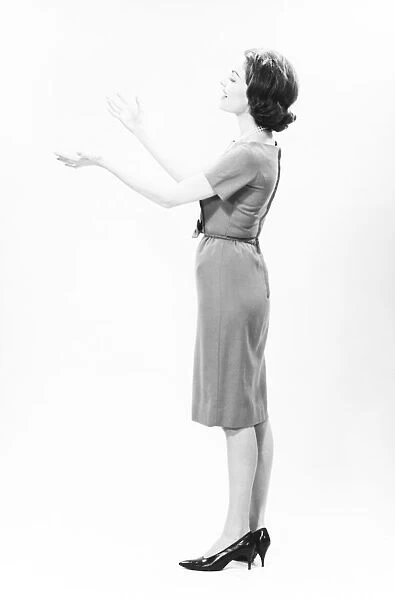 Elegant woman standing in studio, gesturing, (B&W)
