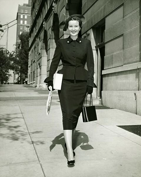 Elegant woman walking on sidewalk, (B&W)