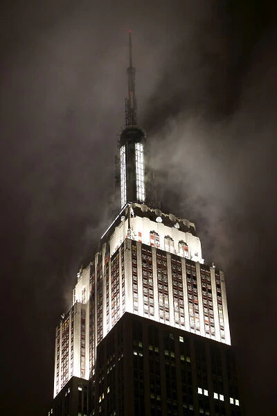 Top of Empire State Building in clouds at nght