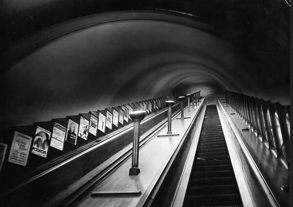 Escalator. circa 1930: An escalator on London Underground with posters on show at the side
