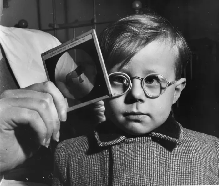Framed Print : Eye Test. 1955: A young boy's eyesight is examined using a glass picture test card Framed Print : Eye Test. 1955: A young boy's eyesight is examined using a glass picture test card