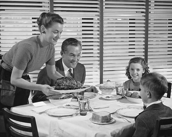 Family dinner, mother holding platter with roast on it