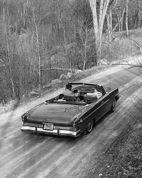 Family driving in convertible along country road