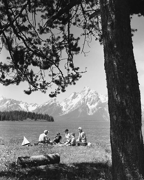 Family having picnic by lake; mountains in background
