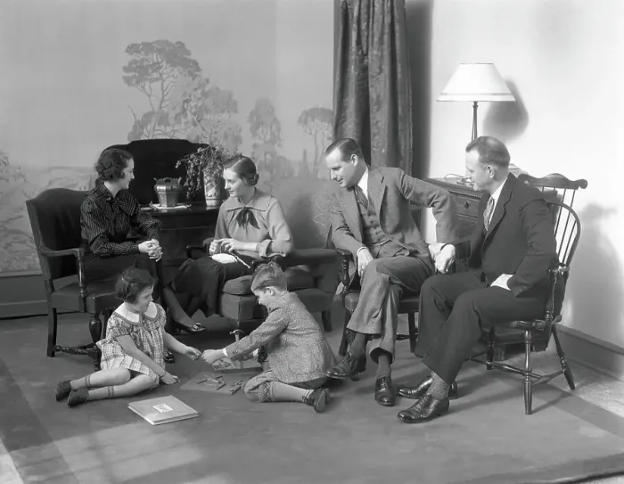 Framed Print : Family in living room daughter and son play on the floor mother and father talk to another couple Framed Print : Family in living room daughter and son play on the floor mother and father talk to another couple