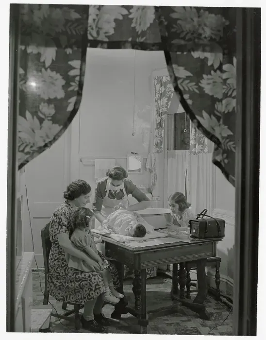 Framed Print : Family Watching Visiting Nurse Changing Diaper on Baby Framed Print : Family Watching Visiting Nurse Changing Diaper on Baby