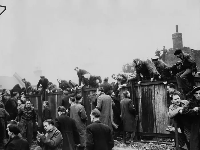 Framed Print : Fans Climb Fence Framed Print : Fans Climb Fence