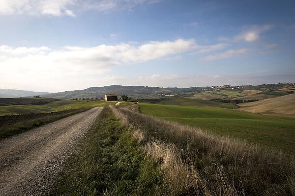 A farm house at the end of dirt road among landscape of Val d Orcia
