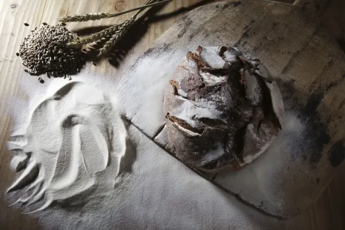 Framed Print : Farmhouse bread on an old bread slide with rye grains, ears and flour on a rustic wooden surface