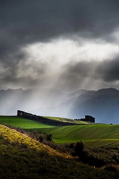 Farmland against dark cloudy sky