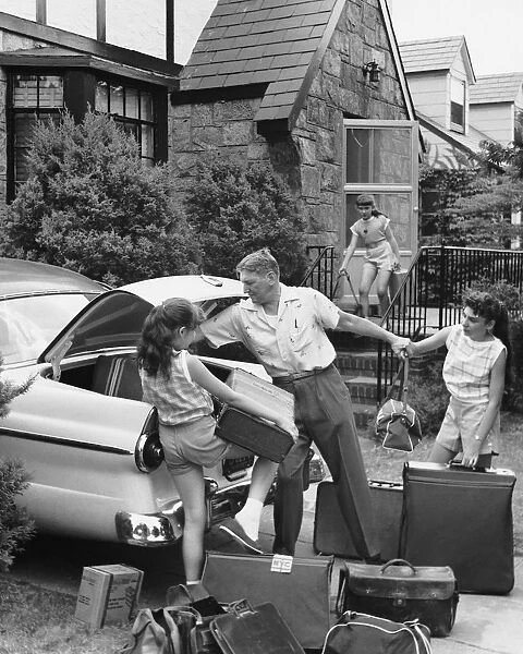 Father and three daughters loading trunk with luggage