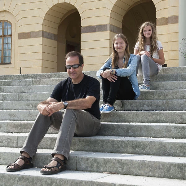 A Father And Two Daughters Sitting On Steps At Drottningholm Palace