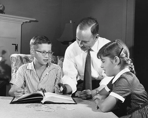 Father helping son and daughter with homework