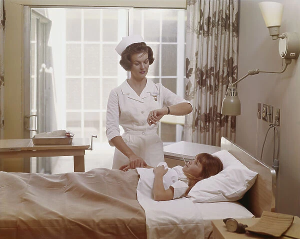 Female nurse checking pulse of girl in bed