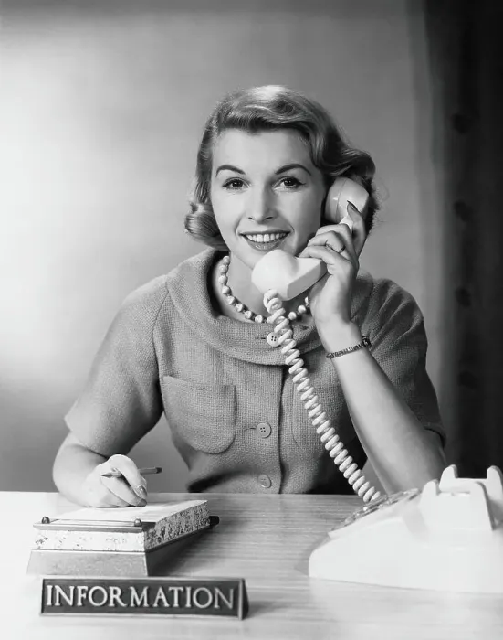 Framed Print : Female telephone receptionist at information desk, answering phone Framed Print : Female telephone receptionist at information desk, answering phone
