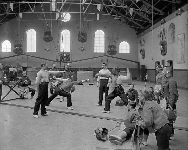 Fencers. circa 1905: A group of men in an Aldershot gymnasium watch a fencing contest