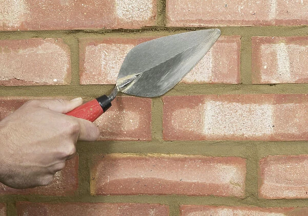 Filling areas of brick wall with mortar using a trowel, close up