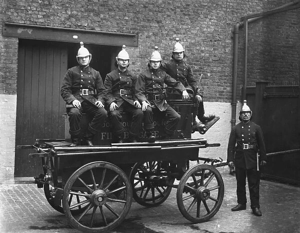 Fire Cart. circa 1905: A group of firemen sit on their fire cart at station headquarters