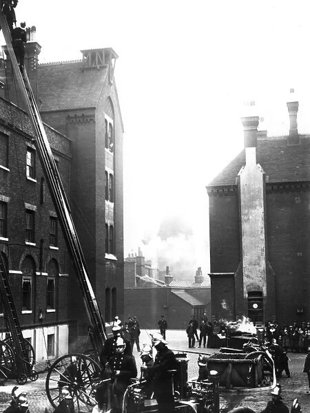 Fire. circa 1910: Firemen at work on a tall building