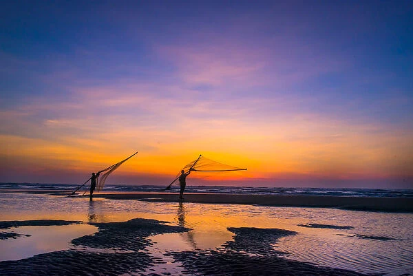 Two Fisherman going on the beach at dawn in Vietnam