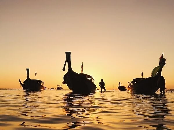 Fisherman and longtail boats at sunset in Thailand
