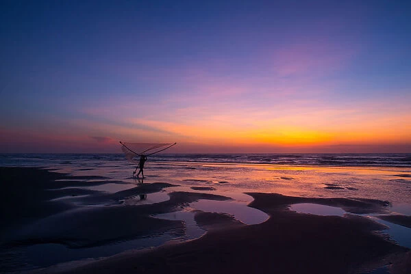 Fisherman walking on the beach at dawn in Vietnam