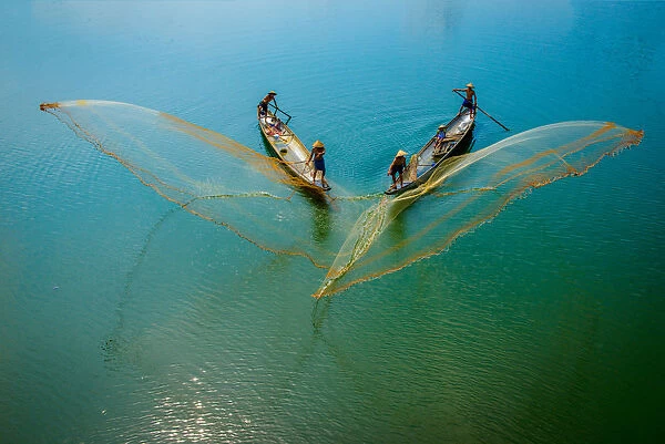 Fishermen throw fishing net on boats to catch fish in Hue