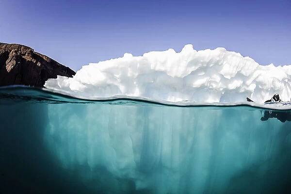 Floating. A small iceberg is being investigated by divers on a sunny summers