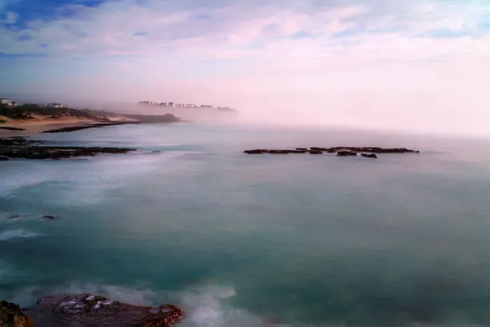 Framed Print : The fog and mist rolling in from the sea envelop the village of Arniston. A long exposure has smoothed the sea and the reflections of pink clouds on the sea are captured, Arniston, Western Cape Province, South Africa