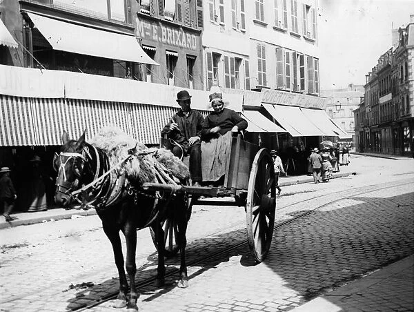 France. circa 1900: Couple driving in a horse and cart up a street in France