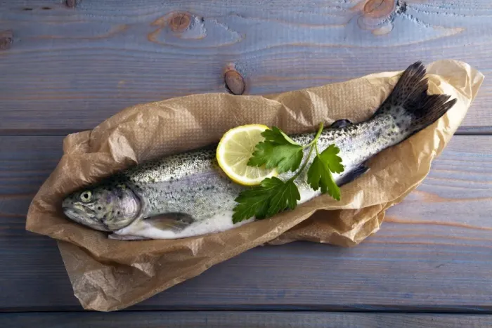 Framed Print : Fresh brook trout in baking paper on a wooden surface Framed Print : Fresh brook trout in baking paper on a wooden surface