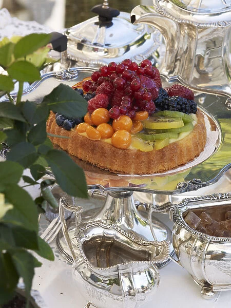 Fruit pie on antique, silver cake plate in a luxurious ambience of a stylishly set coffee table