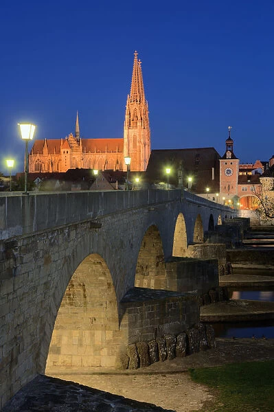 Germany, Bavaria, Regensburg, Cathedral, town gate and stone bridge on Danube river at night