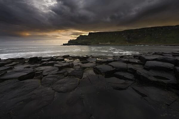 Giants Causeway on moody morning with colorful sunrise