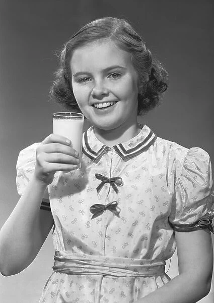 Girl (12-13) posing with glass of milk, (B&W), portrait