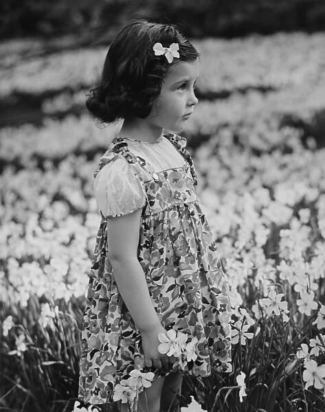 Girl (3-4) standing on blooming meadow, (B&W)