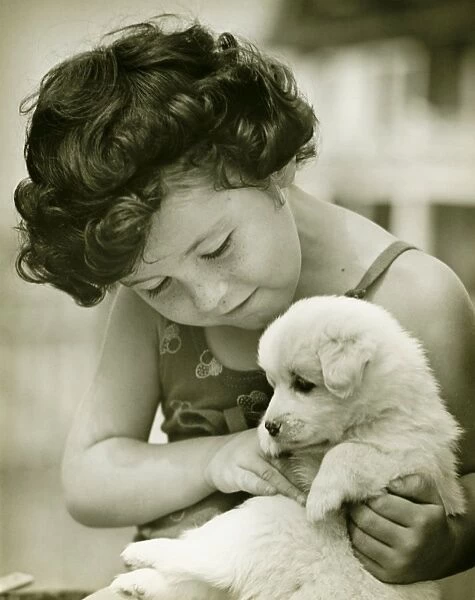 Girl (4-5) holding puppy outdoors, (B&W)