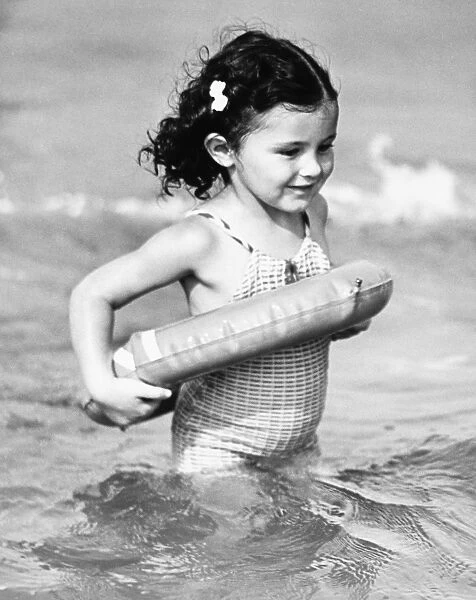 Girl (4-5) standing in water with inflatable ring (B&W)