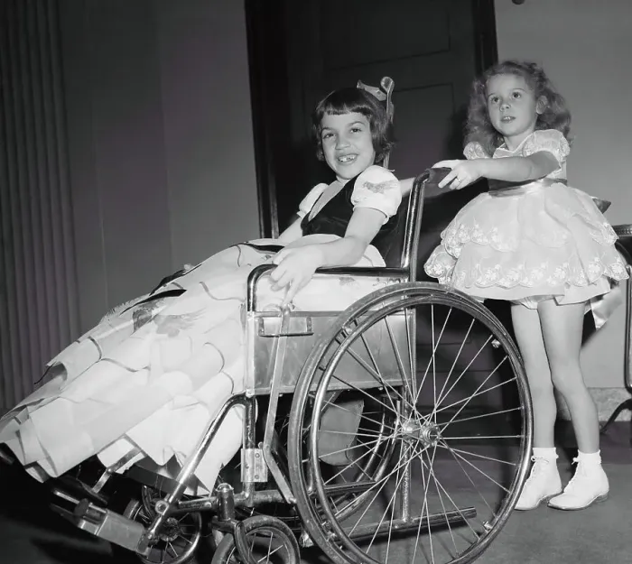 Framed Print : Girl (4-5 years) pushing friend on wheelchair. March of Dimes Fashion Show, Waldorf Astoria, Manhattan, New York City, New York State, USA. January 31, 1950 Framed Print : Girl (4-5 years) pushing friend on wheelchair. March of Dimes Fashion Show, Waldorf Astoria, Manhattan, New York City, New York State, USA. January 31, 1950
