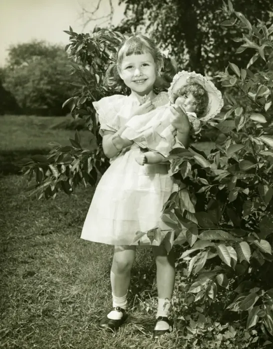 Framed Print : Girl (6-7) holding doll, posing in park, (B&W), (Portrait) Framed Print : Girl (6-7) holding doll, posing in park, (B&W), (Portrait)