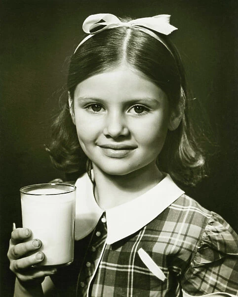 Girl (6-7) holding glass of milk, posing in studio, (B&W), close-up, portrait