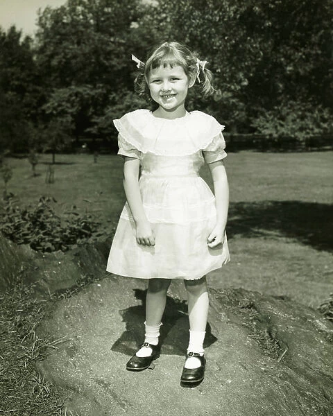 Girl (6-7) in white dress posing in park, (B&W), (Portrait)